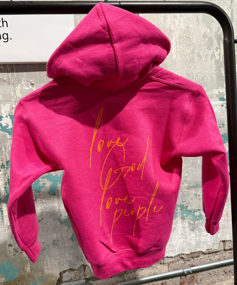 Pink hoodie with text on a textured wall background