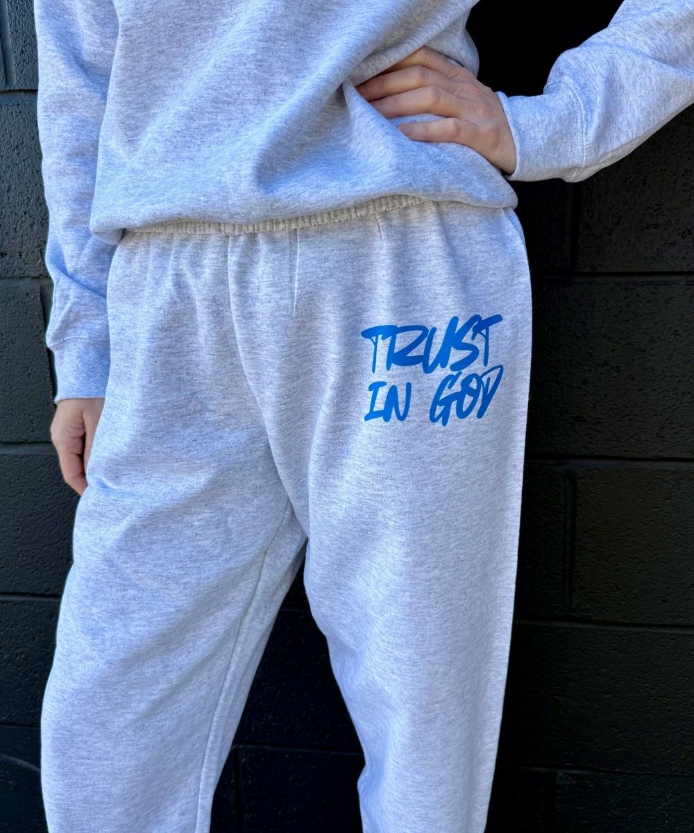 Gray sweatpants with 'Trust In God' text in blue on a black background